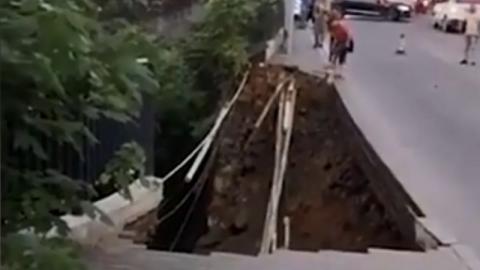 重庆昨天（7月27日）晚间突然发生道路塌陷意外，当时2名路人瞬间坠入巨坑内，场面令人怵目惊心。（视频截图）