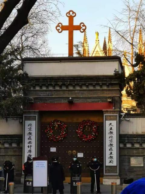 12月24日平安夜，网上传出的照片显示，北京一所天主教堂，一排手持防暴器械的警察守在门口，一块告示上写着暂停一切活动。网友嘲讽说，想过圣诞节，还得先过警察这一关。（网络图片）