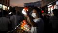 2020年6月10日中国湖北省武汉市一个户外市场上，摆摊卖服装的摊主正举著灯等候顾客光顾。(STR/AFP via Getty Images)