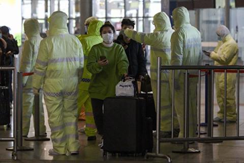 2月9日上海南火车站，穿上防护衣的医护人员查阅乘客的旅游行程。(NOEL CELIS/AFP)