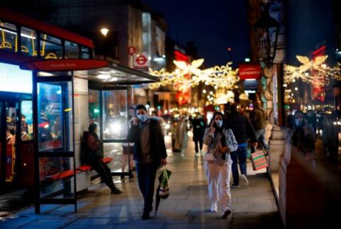 2020年12月19日，行人和购物者戴着口罩走过皮卡迪利（Piccadilly）的商店。(TOLGA AKMEN/AFP via Getty Images)